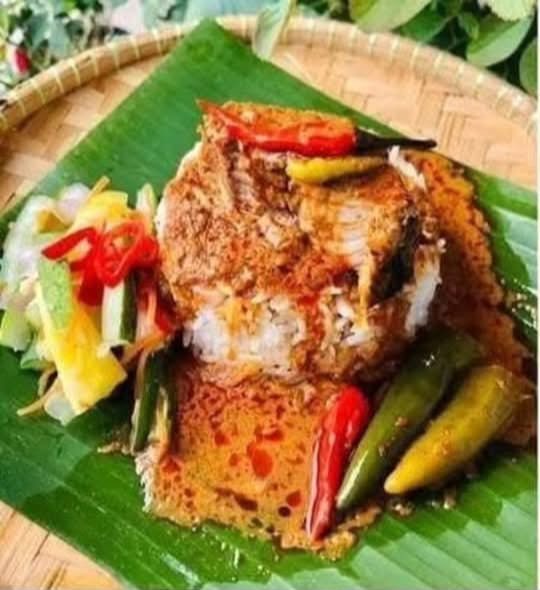 Nasi dagang dengan gulai ikan, acar timun dan cili di atas daun pisang